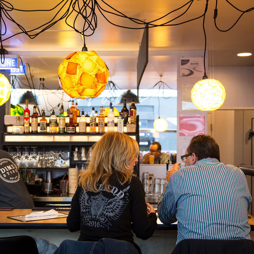Guests enjoying brunch at the vintage bar inside Dime Store Detroit with swag lamps and liquor shelves